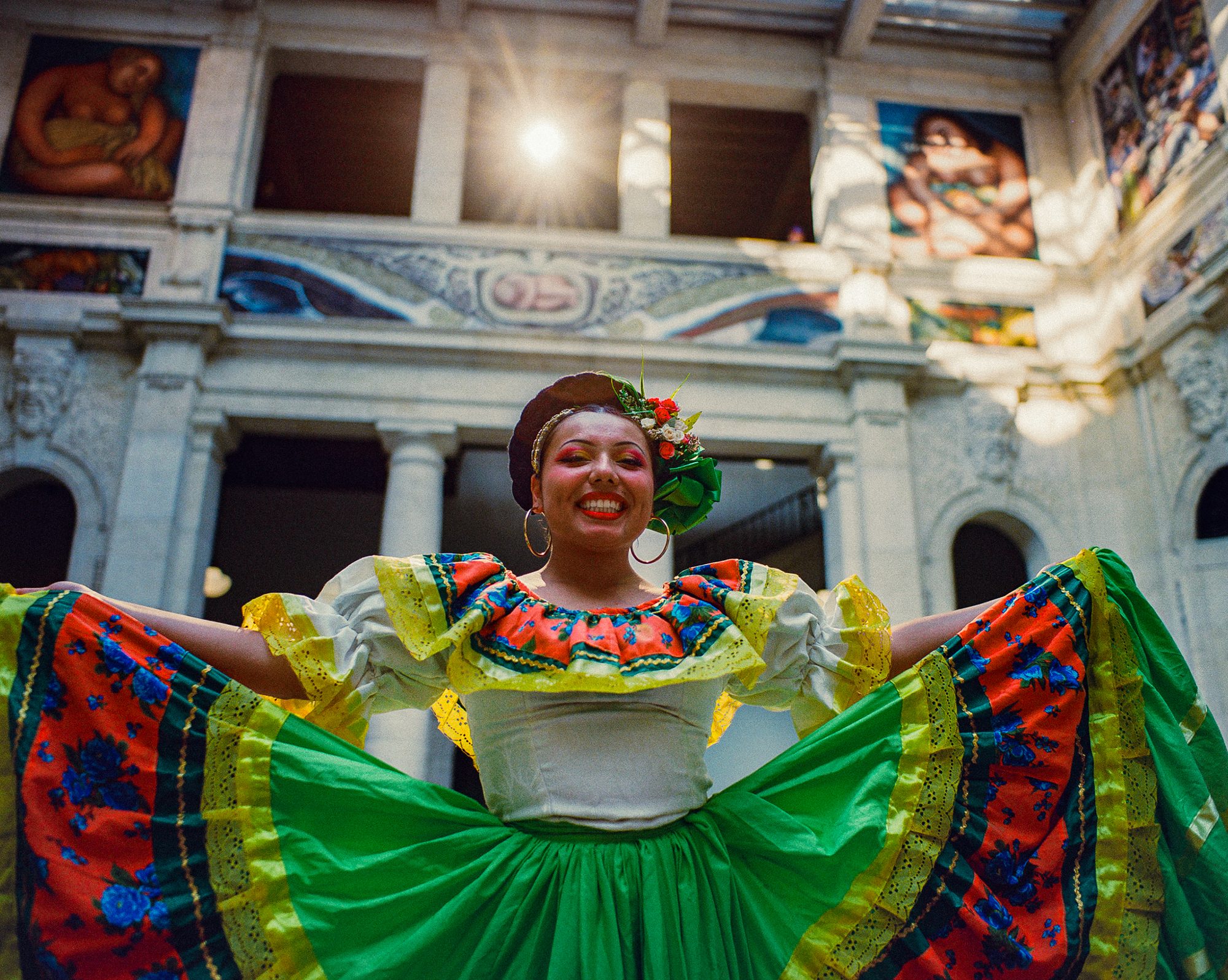 Folklórico dancer smiling with her bright skirt spread wide